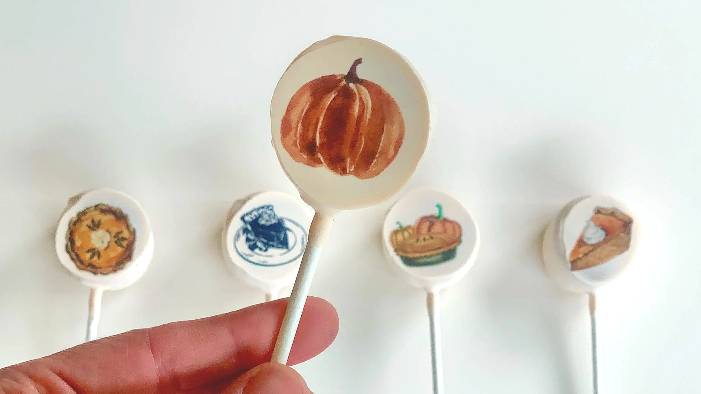 Five individually wrapped cake pops lined up on a marble and cloth background 